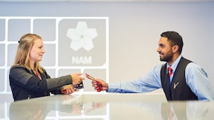 Mannelijke beveiligingsbeambte reikt bezoekerspas uit aan vrouw