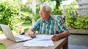 Meneer achter een laptop met papieren voor zich