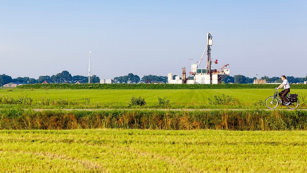 Groen weiland met fietser op fiets pad, in de verte een winningslocatie