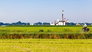 Groen weiland met fietser op fiets pad, in de verte een winningslocatie