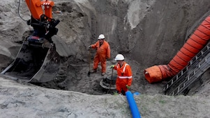 Twee medewerkers in oranje overall in afgraving