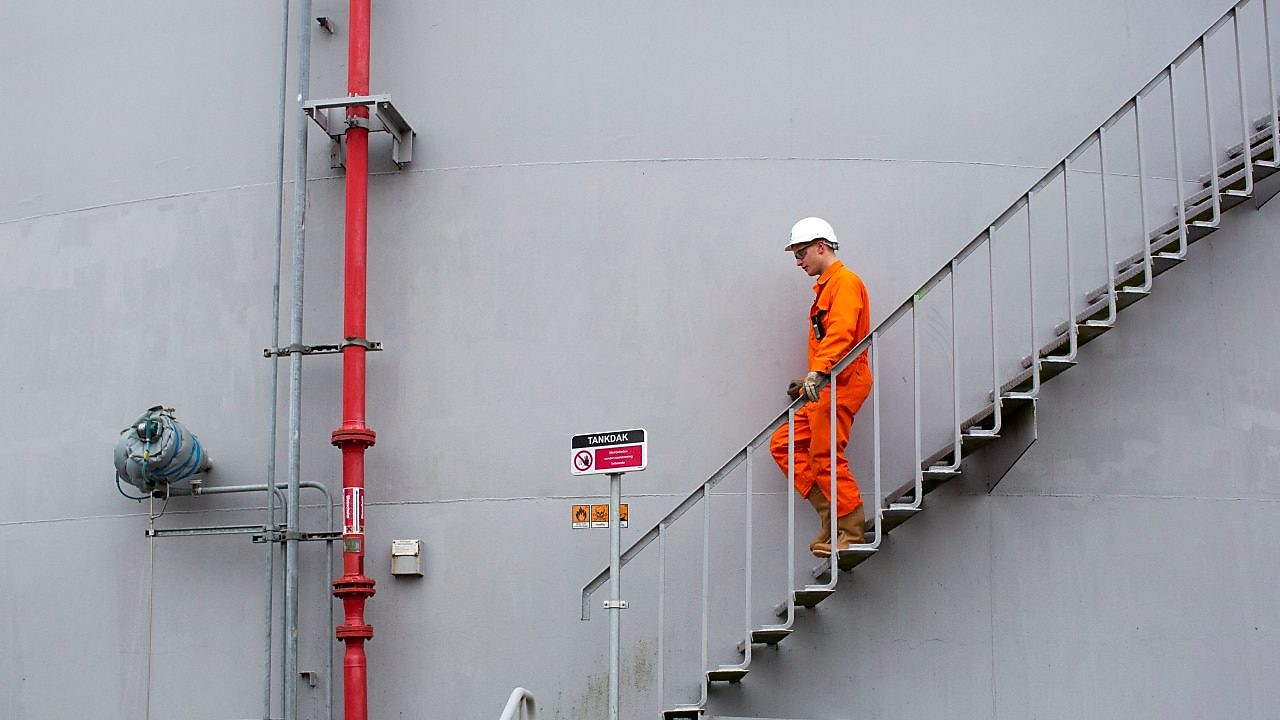 Medewerker in oranje overall loopt een ttrap af met zijn hand aan de leuning