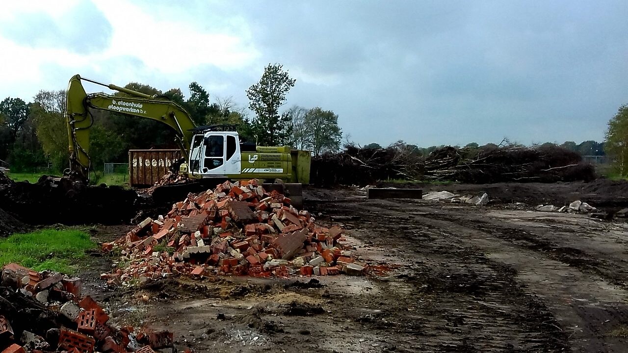 Graafmachine bij afgegraven grond met berg puin