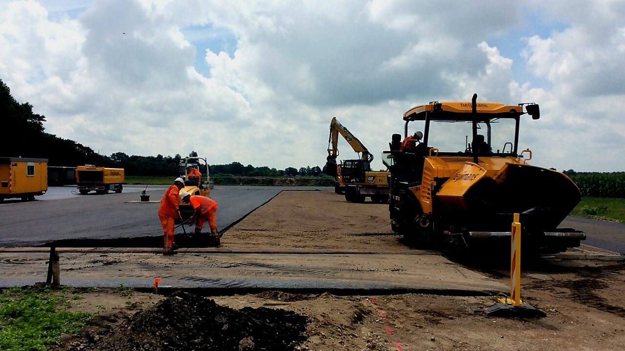 Medewerkers asfalteren een terrein met asfalteermachine