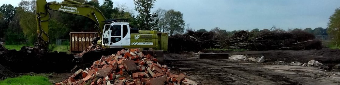 Graafmachine bij afgegraven grond met berg puin