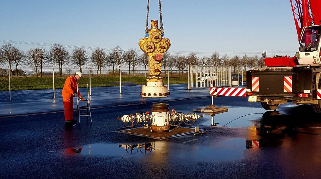 Medewerker in oranje overall bij kraan die gele afsluiter plaatst