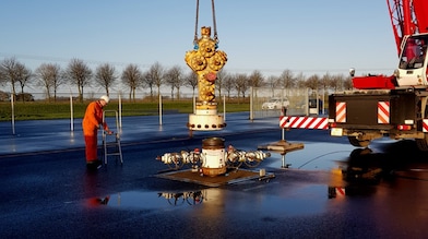 Medewerker in oranje overall bij kraan die gele afsluiter plaatst